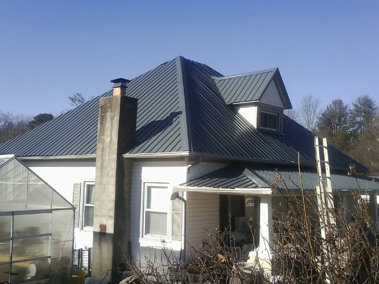 Dark blue standing seam metal roof on a white farmhouse with dormer — Slate & Tile Roof Repair by Roofing Brothers in Ethelsville