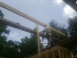 Carpenter setting a ridge beam over a new addition frame — Ice Dam Removal by Roofing Brothers in Ethelsville