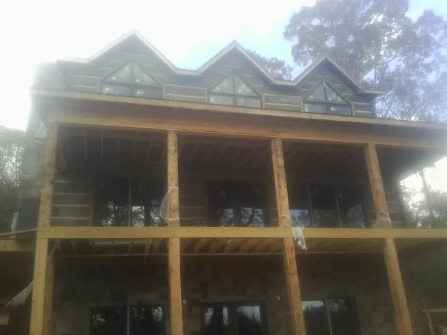Dormers and porch framing on a large log home under construction — Roof Coating work by our crew in Ethelsville