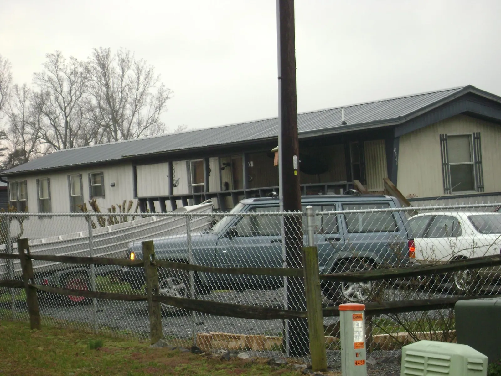 Dark metal roof on a long single story building behind a chain link fence in Ethelsville