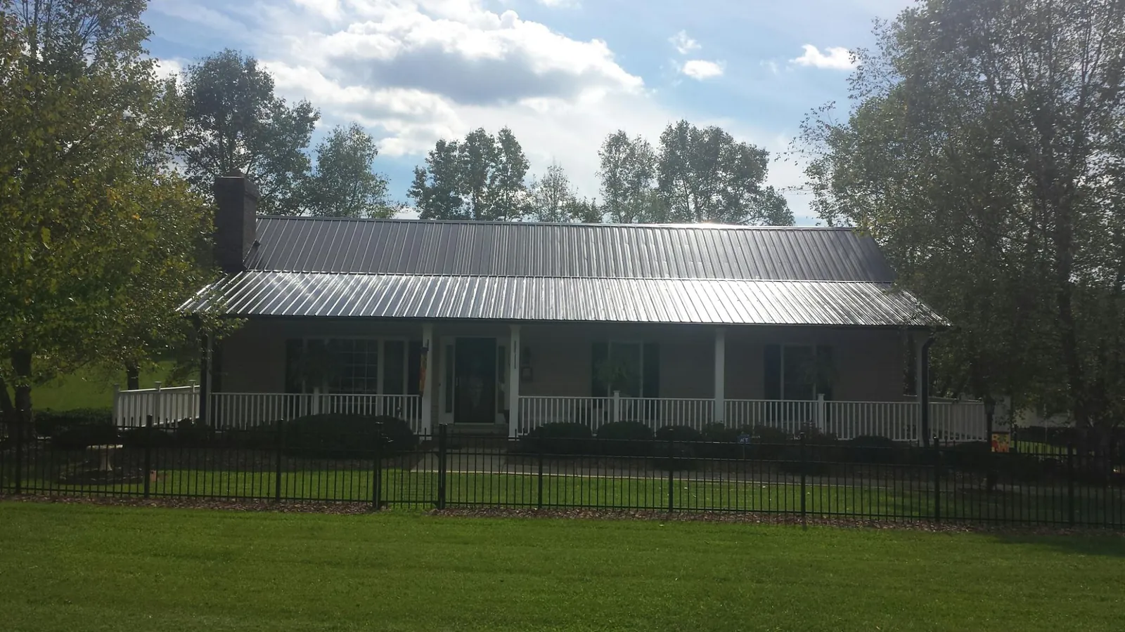 Gray metal roof on a brick ranch with a full width front porch — Gutter Guard Installation work by our crew in Ethelsville