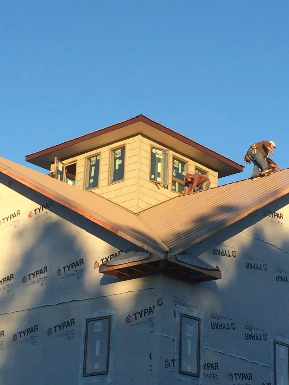 Roofers working around a rooftop cupola on a new metal roof at sunset — Roof Waterproofing in Ethelsville by Roofing Brothers